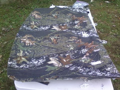 1989 Ford Bronco - A piece of camouflage fabric is laid out outdoors, possibly a seat cover or tarp.