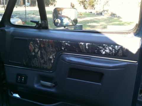 1989 Ford Bronco - The interior door panel features a camouflage insert, with power window controls visible below the armrest.