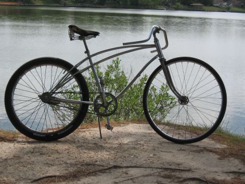 1994 Ford Bronco - A vintage-style cruiser bicycle sits on a sandy shore next to a calm body of water.