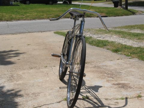 1994 Ford Bronco - A vintage bicycle with chrome handlebars and a leather seat sits on a cracked concrete surface.