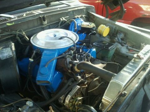 1979 Ford Bronco - The engine bay of a vehicle, blue painted valve covers and a prominent air filter housing.