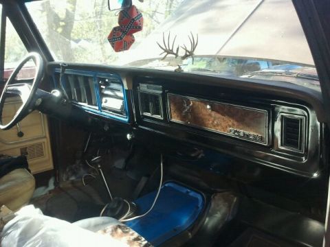 1979 Ford Bronco - The interior of a 1979 Ford Bronco shows a woodgrain dashboard with a "CUSTOM" badge and a deer antler ornament on the dash.