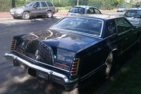 1991 Ford LTD Crown Victoria - A dark coupe with a continental kit is parked on a street, with other vehicles visible in the background.