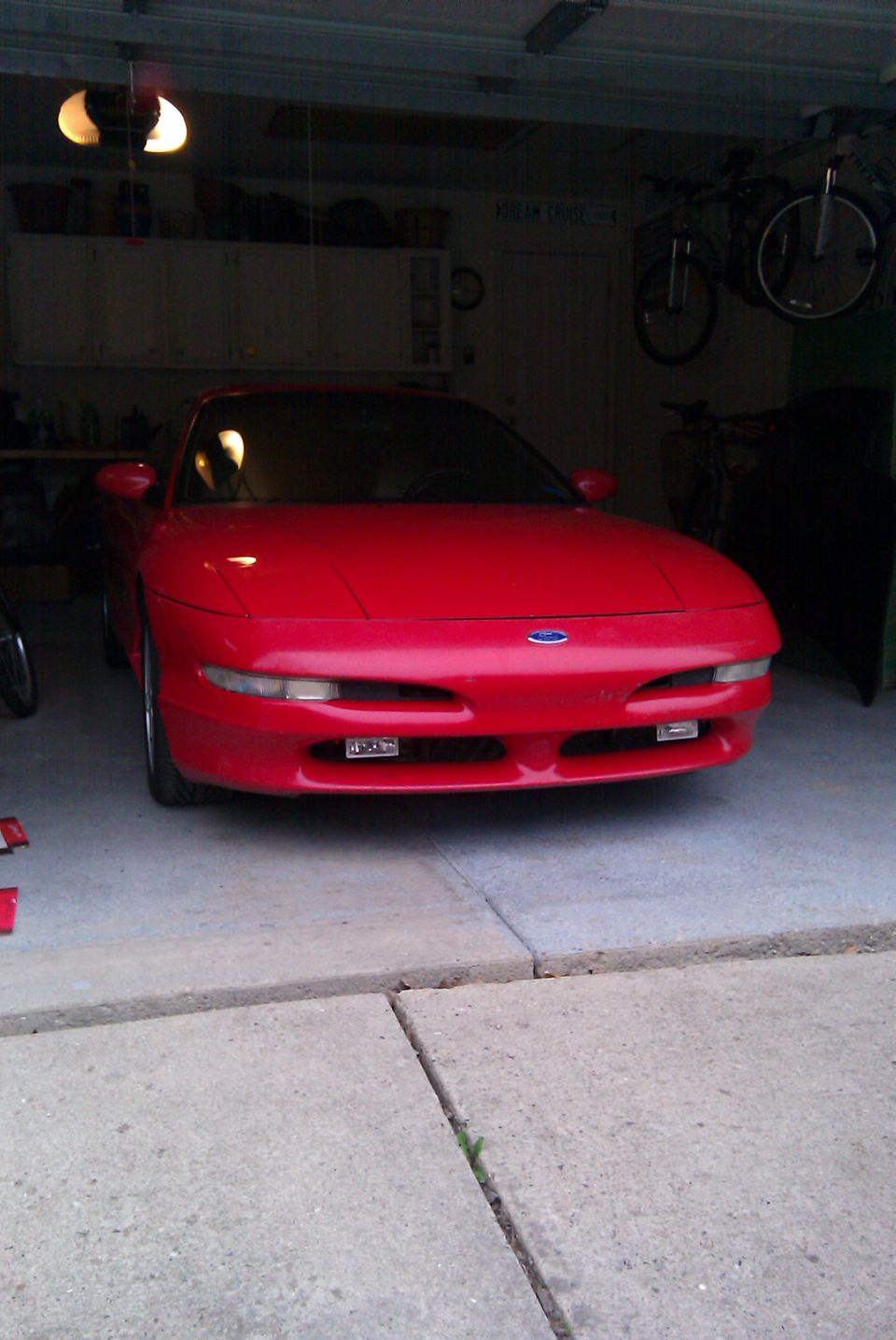 Red Ford Probe coupe parked in a garage, front view with headlights closed