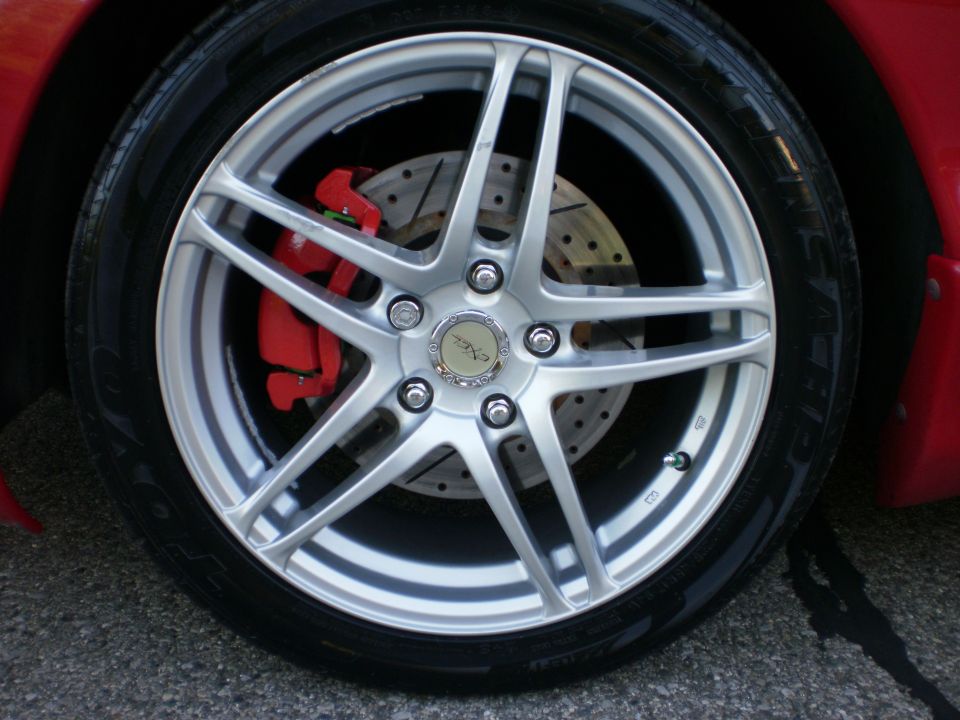 Close-up of a silver five-spoke wheel with a red brake caliper visible behind it