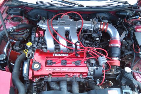 1996 Ford Probe - Close-up of a Mazda V6 DOHC 24-valve engine, red spark plug wires and intake piping.