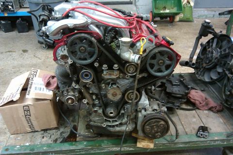 1996 Ford Probe - Engine assembly with timing belt and pulleys visible, resting on a stand with a box of parts.