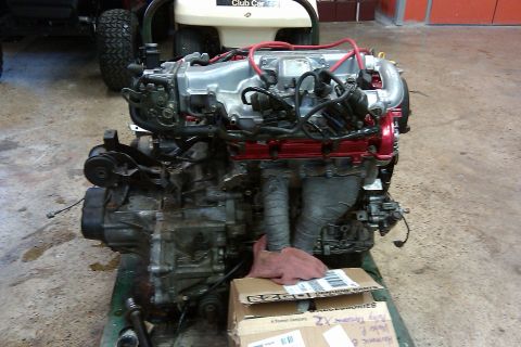 1996 Ford Probe - Engine assembly with visible wiring and exhaust components, placed on a green stand.