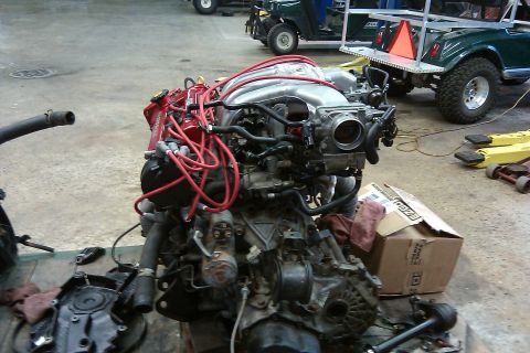 1996 Ford Probe - Engine assembly with red spark plug wires and silver intake manifold, possibly from a 1996 Ford Probe.