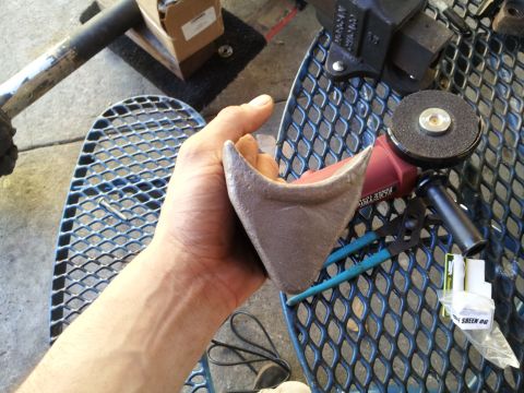 1978 Ford Bronco - A hand holds a metal component next to various tools, including a grinder and pliers, on a mesh surface.