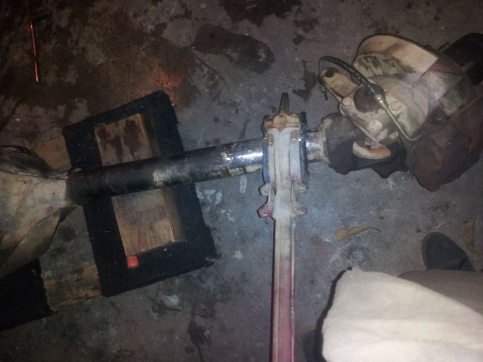 Differential housing with brake lines and U-joint yoke, resting on wooden blocks