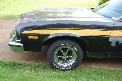 1975 Ford Ranchero - Front quarter view of a black 1975 Ford Ranchero with a gold stripe and chrome accents.