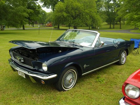 2007 Ford Mustang - A classic dark blue convertible is displayed outdoors with its hood up, next to a red vehicle.