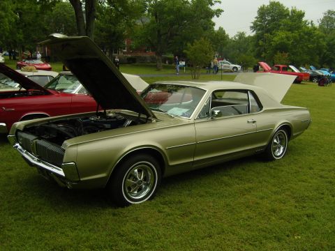 2007 Ford Mustang - A classic gold 1968 Mercury Cougar is displayed with its hood and trunk open at an outdoor event.