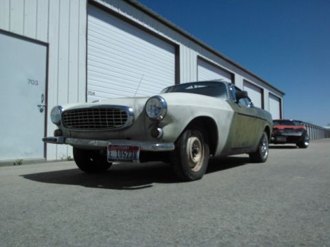 1969 Volvo P1800 - A 1969 Volvo P1800 is parked outside storage units, with another vehicle visible behind it.