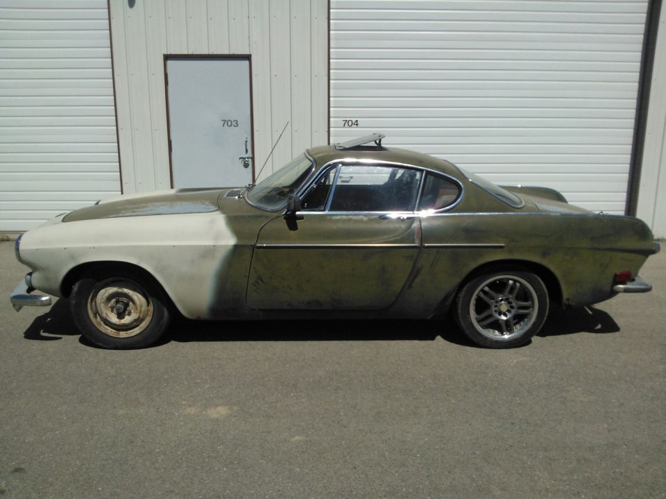 Side view of a 1969 Volvo P1800 with primer on the hood and faded green paint