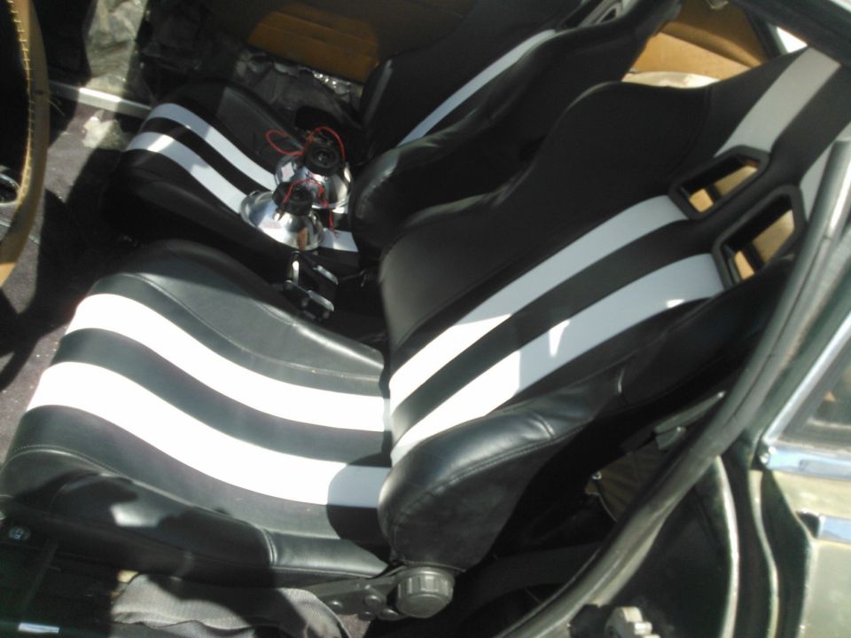 Pair of black racing bucket seats with white stripes installed in a vehicle