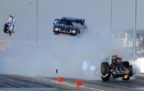 2007 Ford Mustang - Drag cars are captured in a dramatic mid-air moment during a race, with one vehicle tumbling and the other emitting smoke.