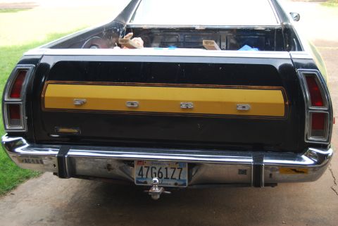 1975 Ford Ranchero - Rear view of a black Ford Ranchero with a yellow tailgate panel and chrome bumper.