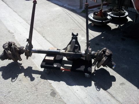 1978 Ford Bronco - A Dana 60 axle assembly is shown on a creeper dolly, with brake drums visible in the background.