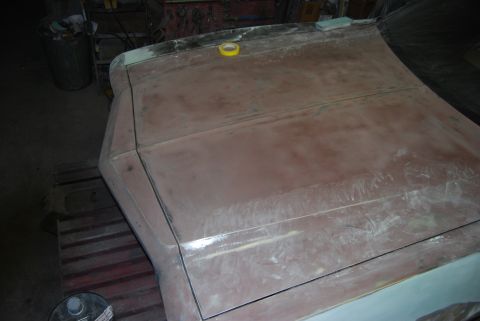 1975 Ford Ranchero - Bodywork is underway on a vehicle's hood and fender area, showing primer and tape.