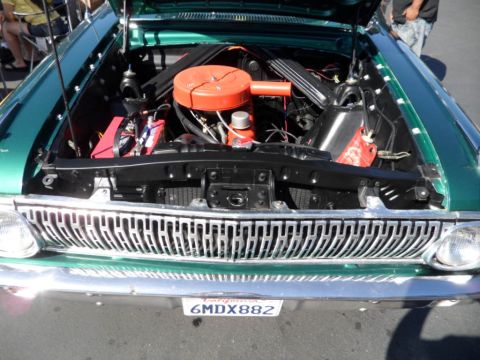 1994 Jeep Cherokee - The engine bay of a green classic car is visible, an orange air cleaner and a prominent chrome grille.