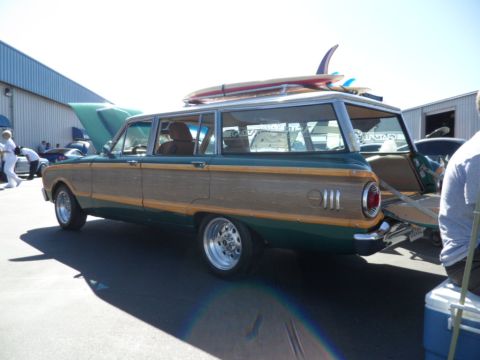 1994 Jeep Cherokee - A classic station wagon, possibly a Ford Country Squire, is parked outdoors with surfboards on its roof.