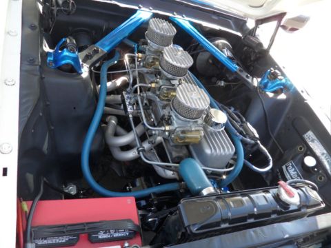 1994 Jeep Cherokee - Engine bay view showing a V8 engine with triple carburetors and custom blue bracing.
