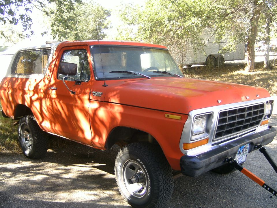 Orange Ford Bronco with a white top, seen from the front-right