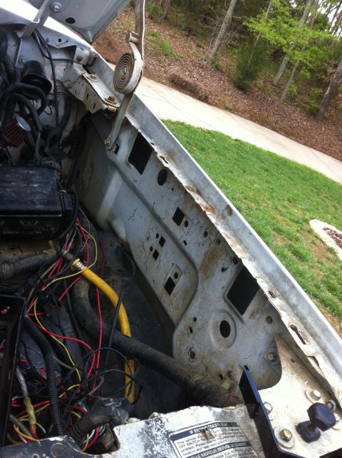 1996 Ford Bronco - Looking down into the open engine bay of a white truck with the inner fender apron stripped bare, exposing factory punch-outs and surface r…