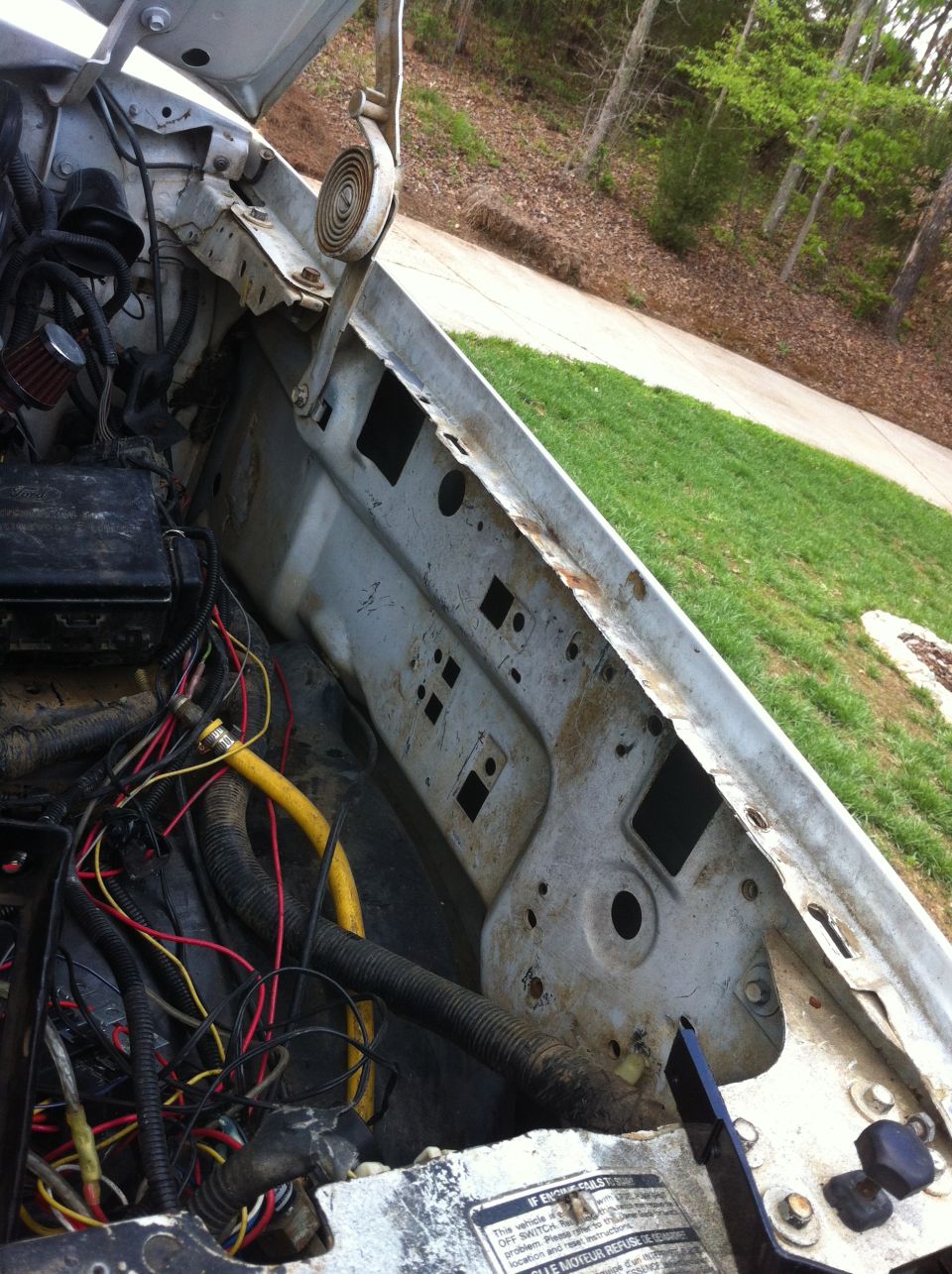 Stripped white truck engine bay showing bare inner fender, loose wiring and Ford fuse box