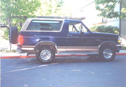 1994 Ford Bronco - A 1992 Ford Bronco is parked on the side of the road, showing its profile and spare tire.