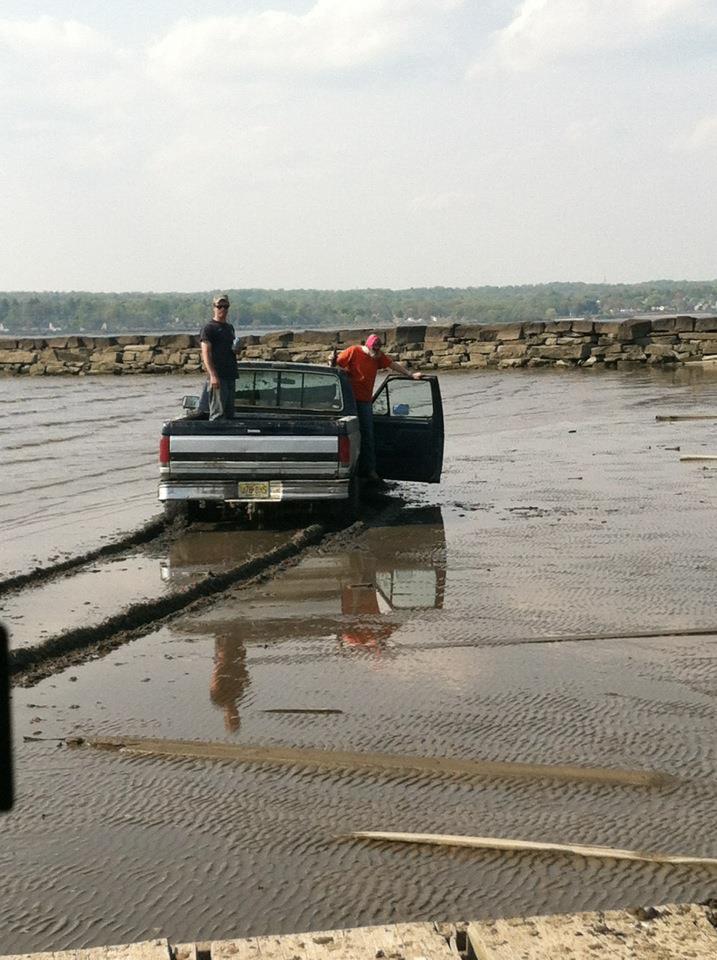 Truck stuck in mud with two people standing around it