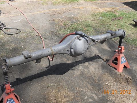 1978 Ford Bronco - A rear axle assembly is supported by two red jack stands on a dirt surface.