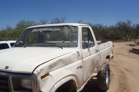 1981 Ford F-150 - Damaged white pickup truck with 'WheelingArizona.com' sticker on windshield.