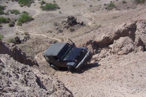 1981 Ford F-150 - A Jeep navigates a challenging off-road path through a dry, eroded landscape.