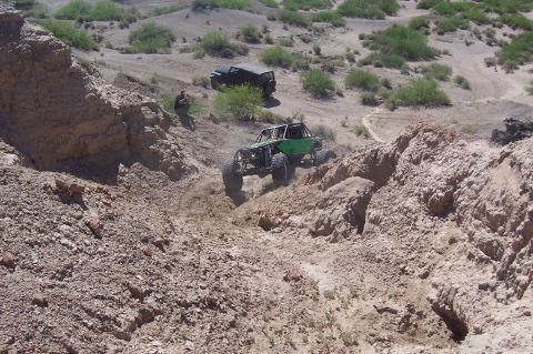 1981 Ford F-150 - Two off-road vehicles navigate a steep, dusty canyon with sparse vegetation.