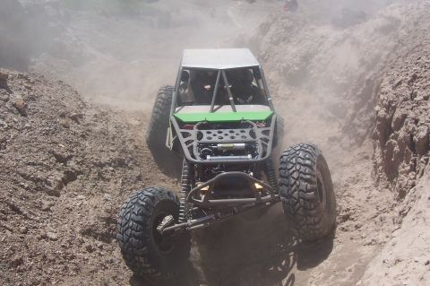 1981 Ford F-150 - Custom off-road buggy navigates a challenging dirt hill climb, generating dust clouds.