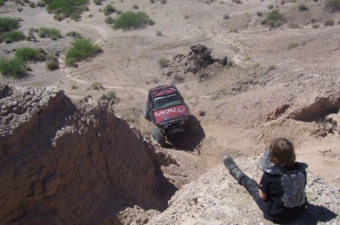 1981 Ford F-150 - Custom off-road vehicle descends a challenging desert trail, observed by a spectator.