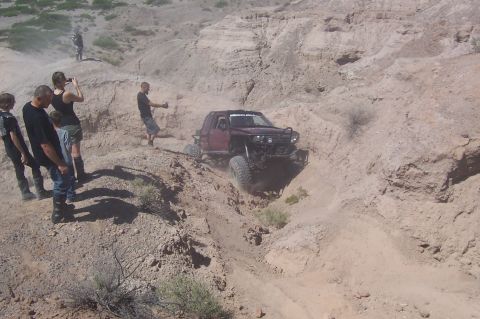 1981 Ford F-150 - A modified truck navigates a challenging off-road trail with spectators observing the action.