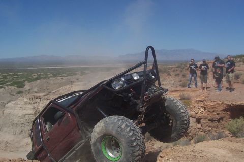 1981 Ford F-150 - An off-road vehicle navigates a steep, rocky incline under a clear blue sky.