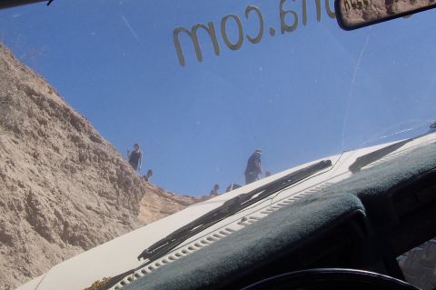 1981 Ford F-150 - Several people are gathered on a cliff overlooking a sandy area, seen through a vehicle's windshield.