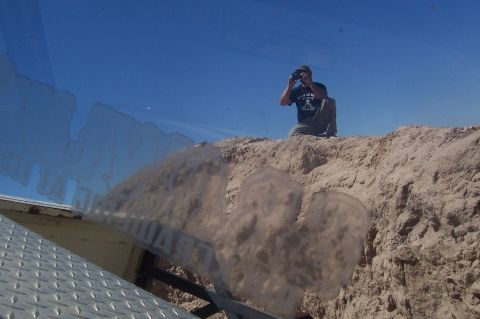 1981 Ford F-150 - A man photographs the landscape from a sand dune, with a vehicle's reflection visible.