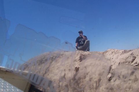1981 Ford F-150 - A person rests on a dusty ridge under a clear blue sky, with the Supermotors logo in the corner.