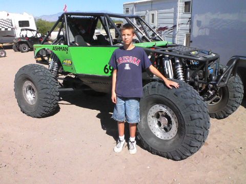 1981 Ford F-150 - A young person poses with a custom-built, bright green off-road buggy in a sandy area.