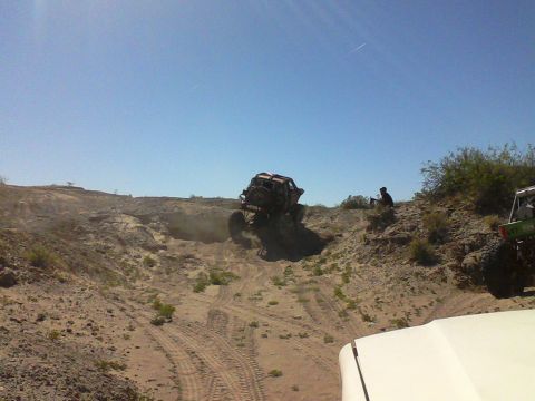 1981 Ford F-150 - Several off-road vehicles navigate a sandy, rocky terrain under a clear blue sky.