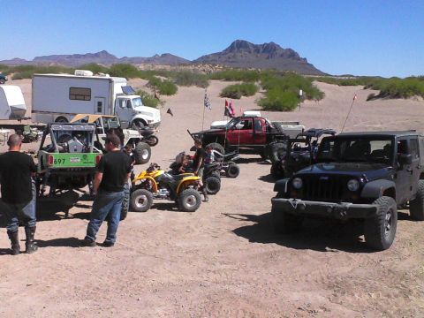 1981 Ford F-150 - A group of off-road vehicles and campers gathered in a desert area on a sunny day.