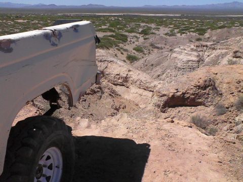 1981 Ford F-150 - A white pickup truck navigates a rocky, arid terrain with sparse vegetation under a clear sky.