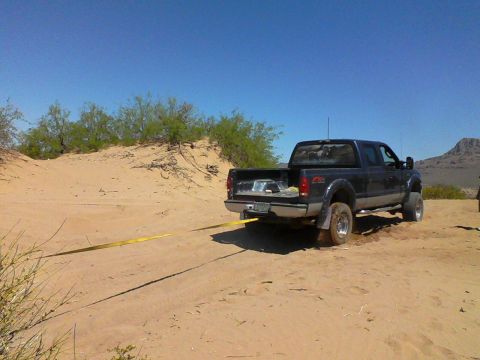 1981 Ford F-150 - Truck stuck in sand with a tow strap attached to the rear hitch.