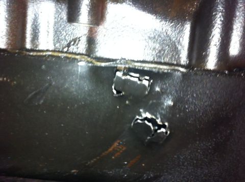 1990 Ford Bronco - Close-up view of a heavily rusted metal panel with two irregularly shaped holes.